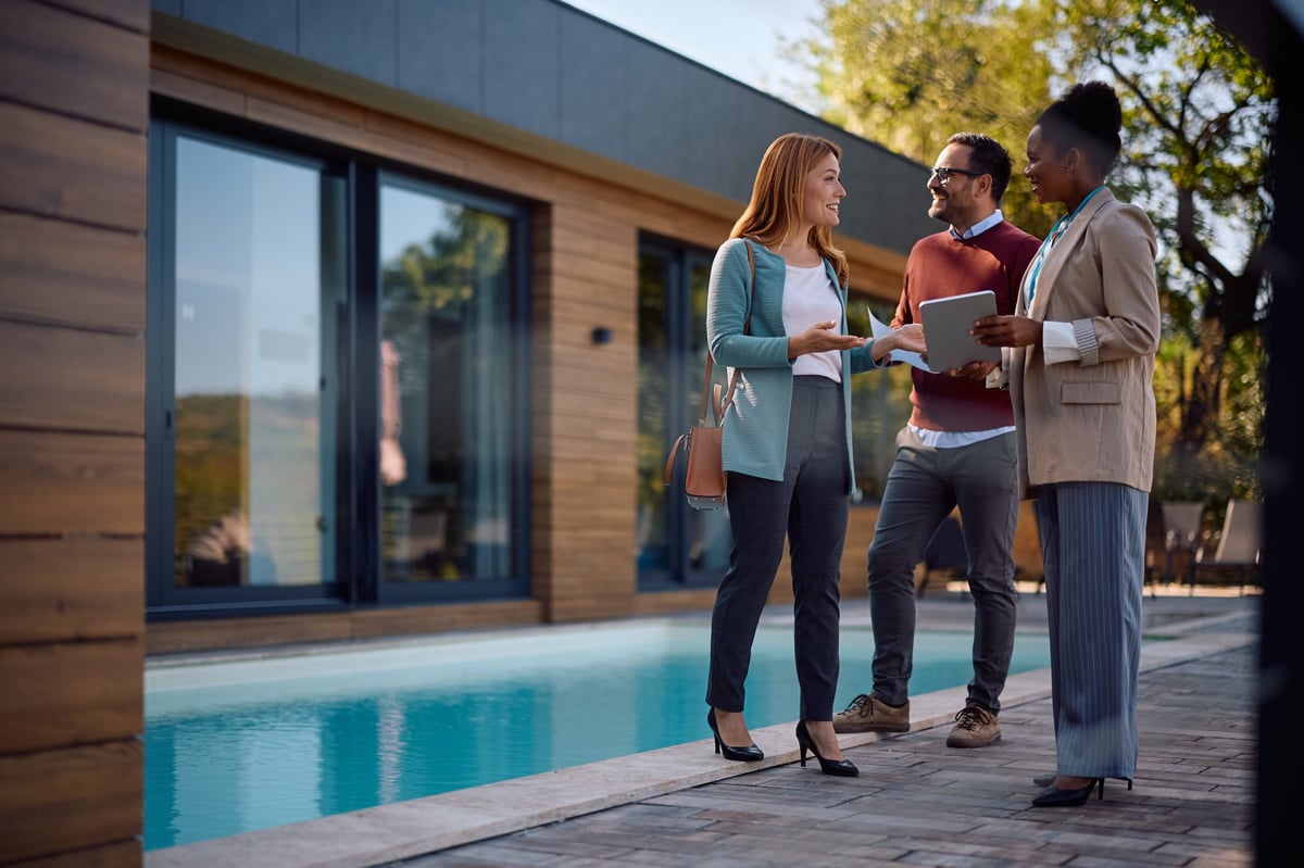Happy woman talking to real estate agent while buying new house with her husband